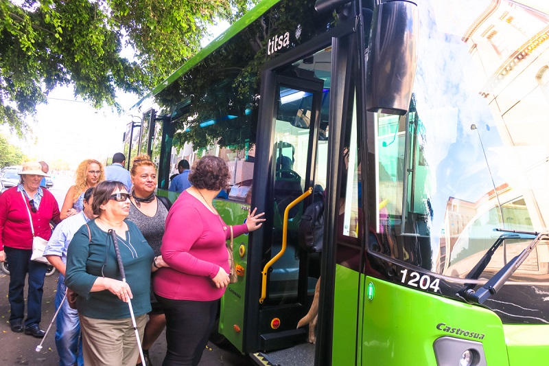 Varias personas con visión reducida suben a un autobús de Titsa.